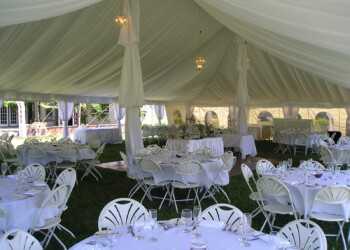 OLYMPUS DIGITAL CAMERA An all white reception setup on a lawn under a white tent.